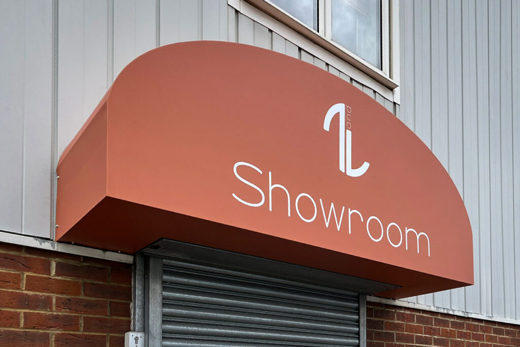 A building entrance features a red awning labeled "Showroom," above a closed metal shutter. Brick and panel walls frame a small window.